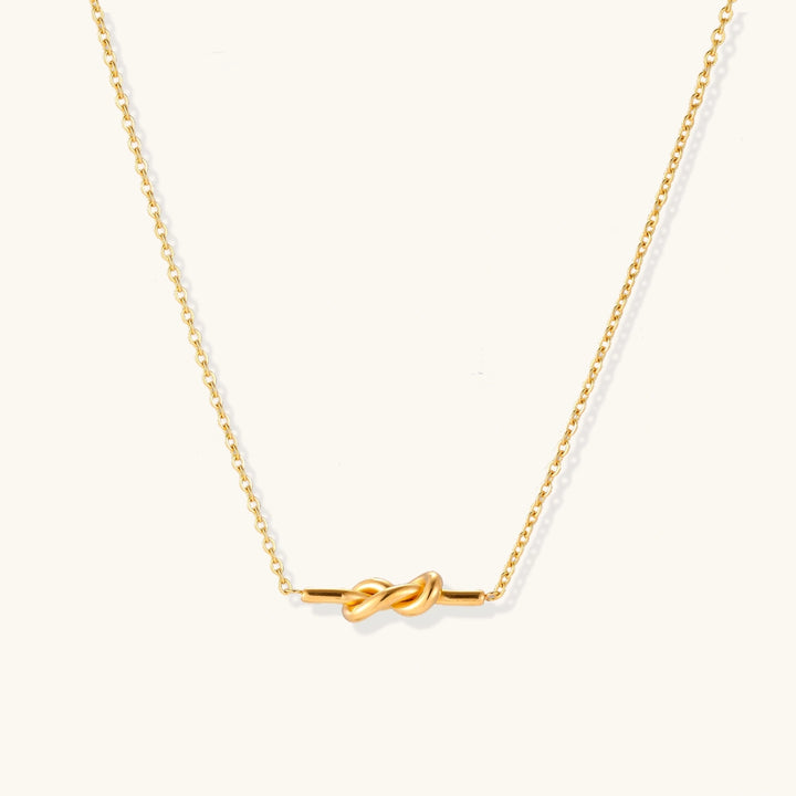 Dainty 18K gold plated necklace with infinity knot pendant on delicate chain against white background